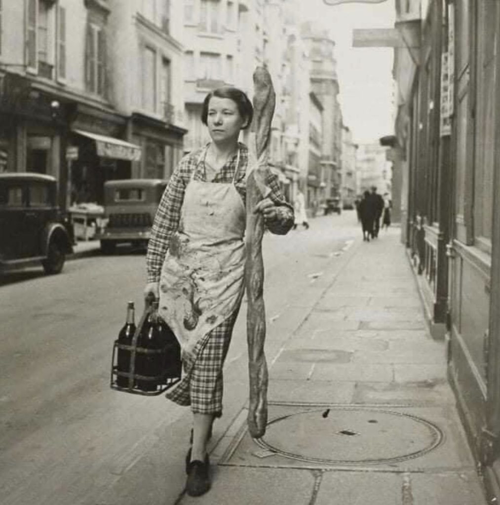 Femme française avec une baguette et six bouteilles de vin (1945)